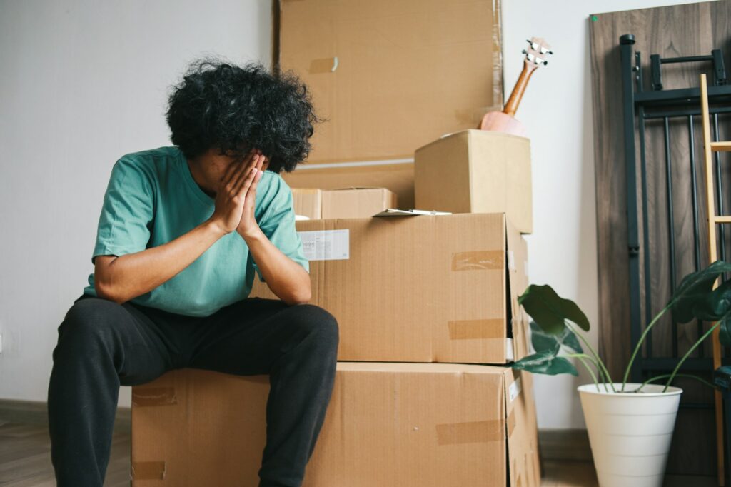 L'angoscia del pignoramento immobiliare: un uomo circondato da scatole di trasloco.