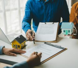 Un agente immobiliare consegna ai clienti campioni di case, discutendo i contratti di mutuo e preparando una proposta di locazione.